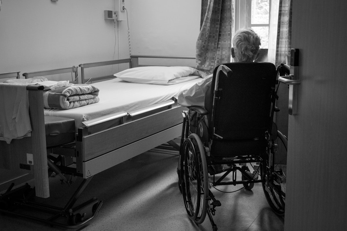 Chambre de maison de repos avec lit médicalisé et résident en fauteuil roulant
